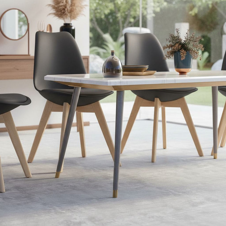Mid-century modern black plastic-shell dining chairs, 4-piece set with wooden legs around a white table.