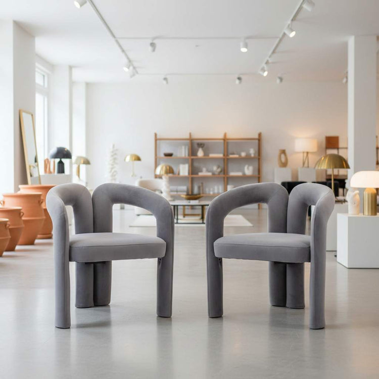 Pair of velvet dining armchairs with curved back, plush upholstery, modern silhouette.