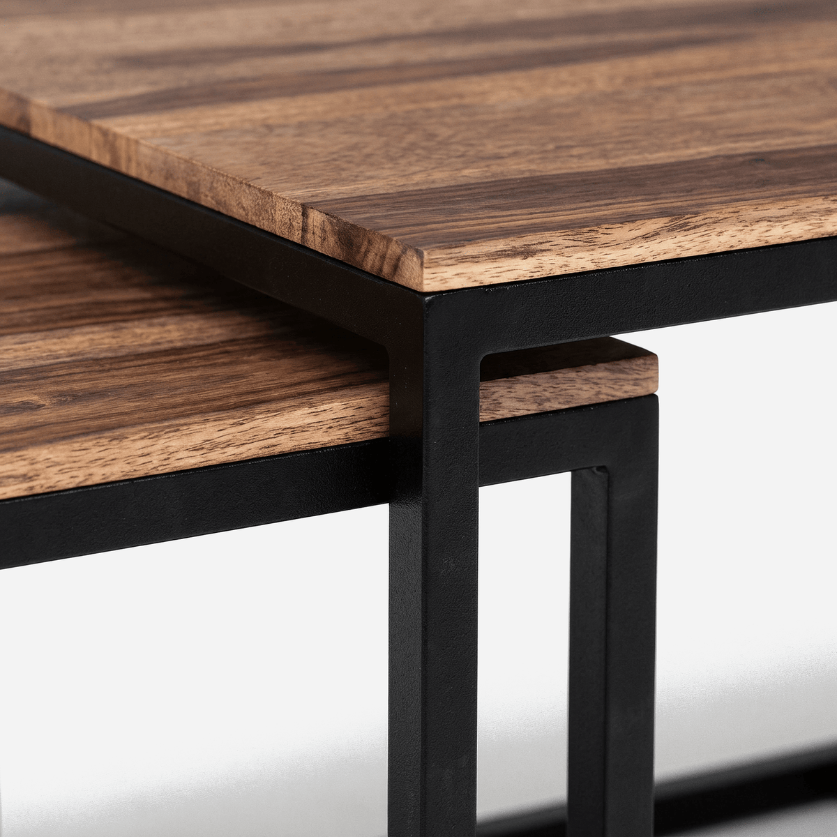 Small sheesham wood table nested under the large table on slim black metal legs (close-up detail)
