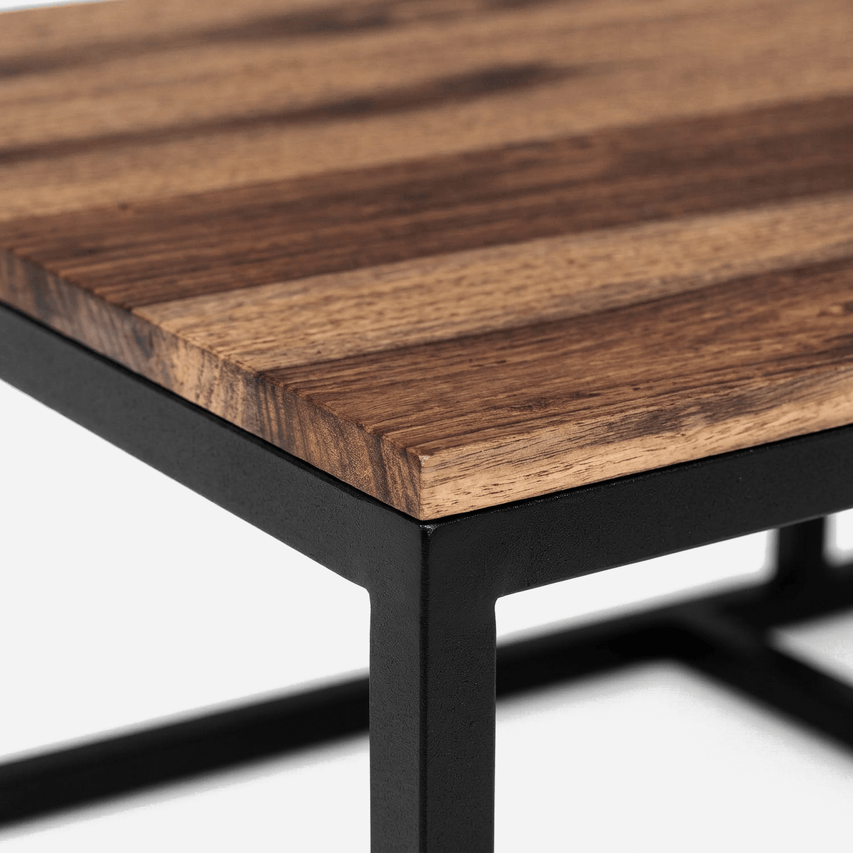 Sheesham wood tabletop with dark streaked grain meeting a black powder-coated metal corner (close-up detail)