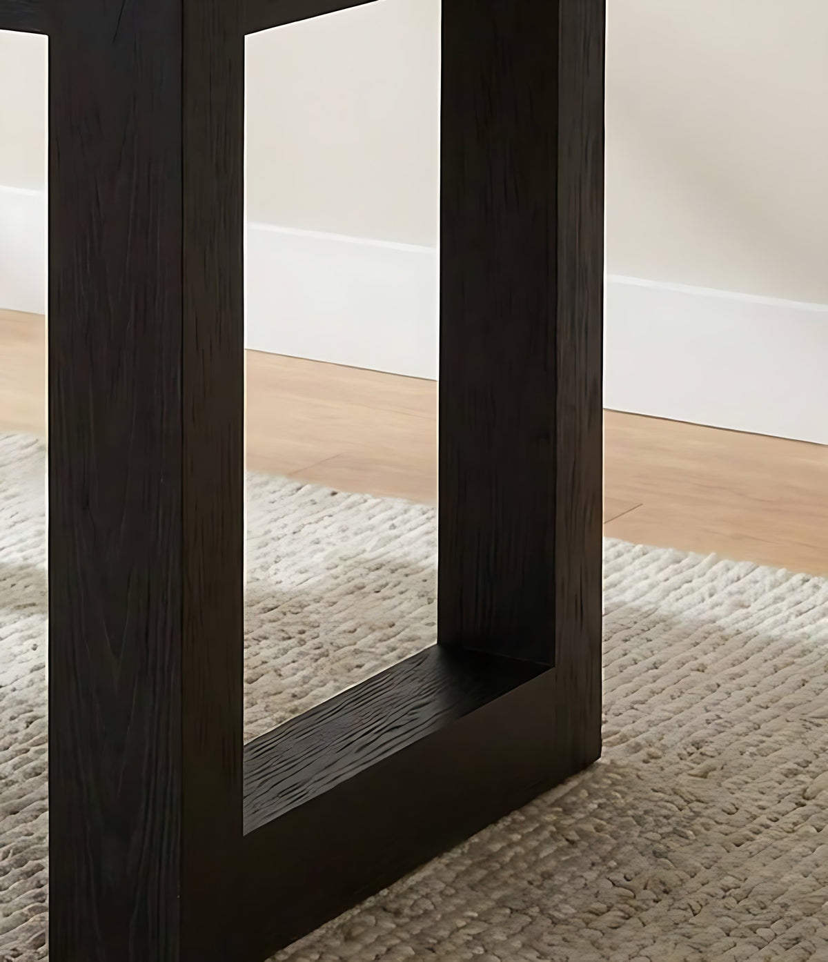 Black wood office desk, close-up of the leg frame on a rug