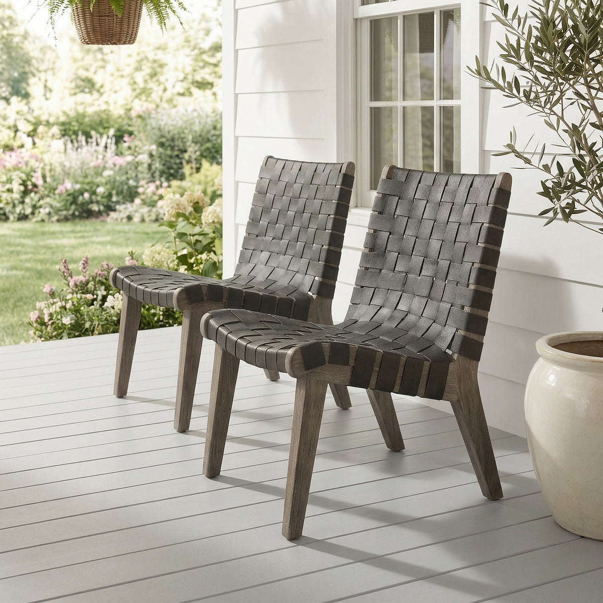 Two outdoor lounge chairs close together on a porch deck facing a flower garden