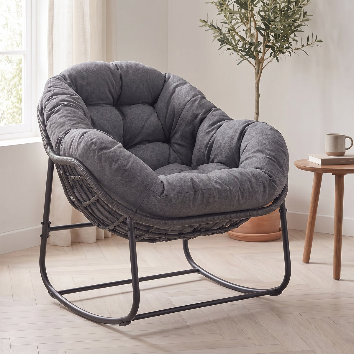 Dark gray papasan rocker in a bright living room beside a round wooden side table