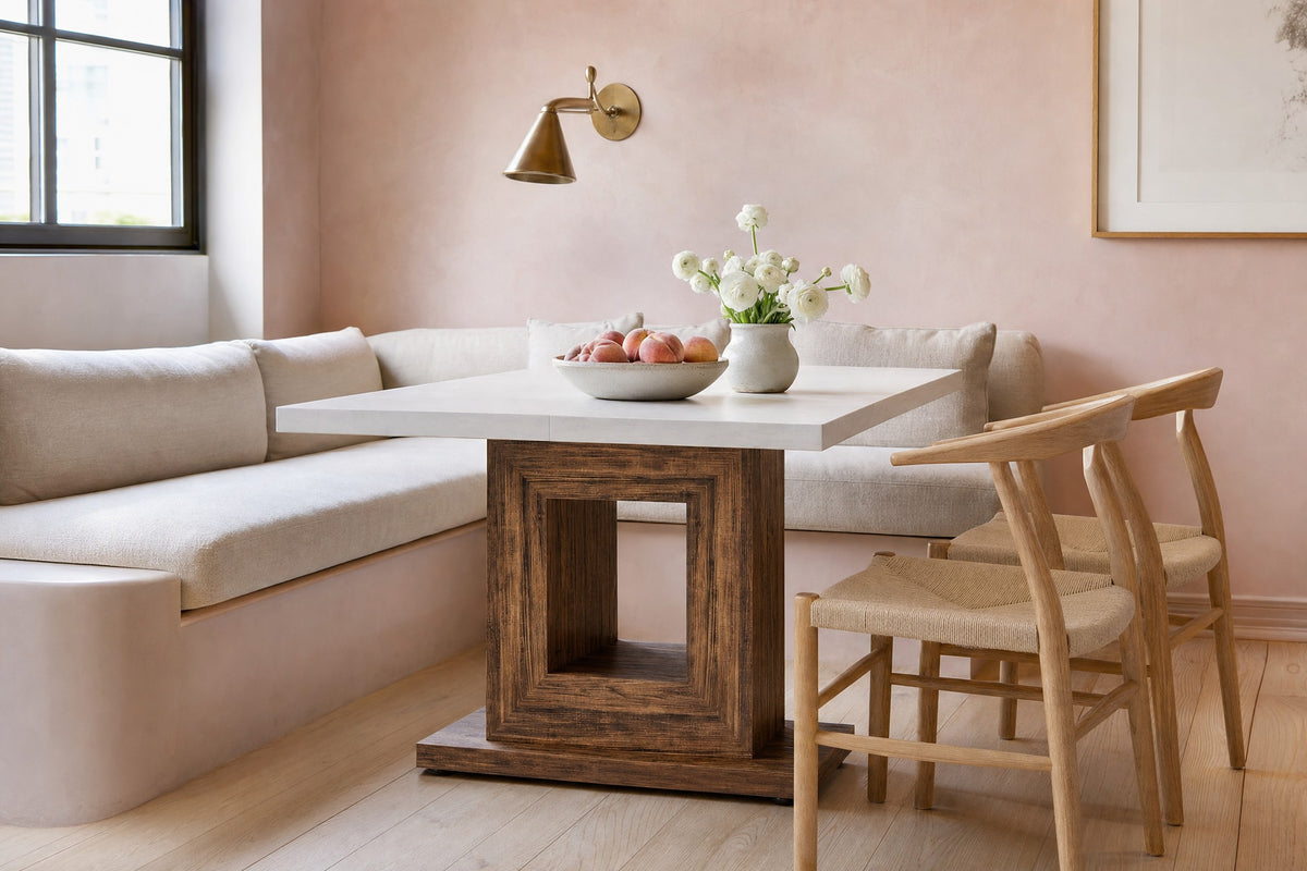 Pedestal dining table in a city breakfast nook with a linen banquette