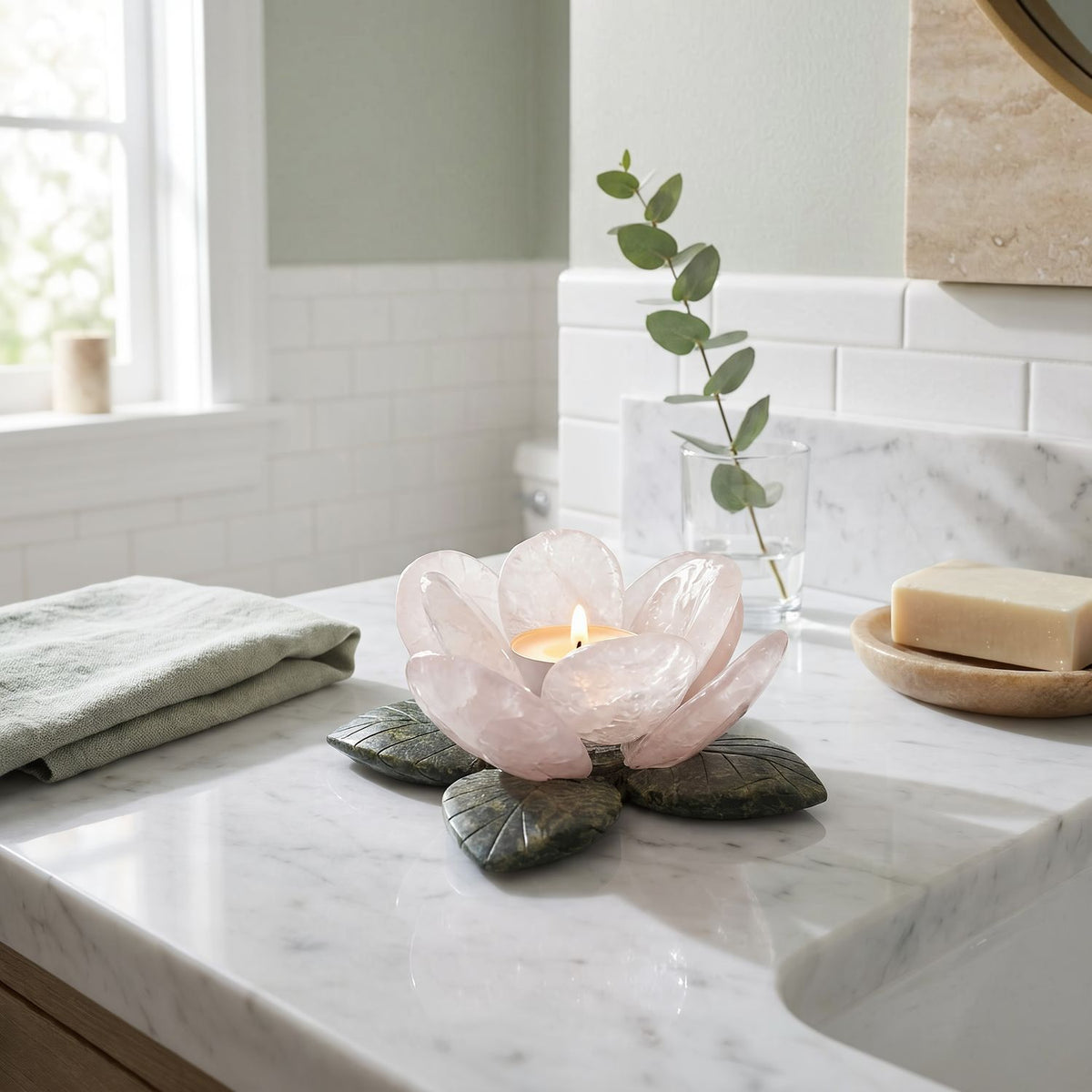 Rose quartz flower candle holder with a lit tealight on a marble bathroom vanity, wide view (room scene)