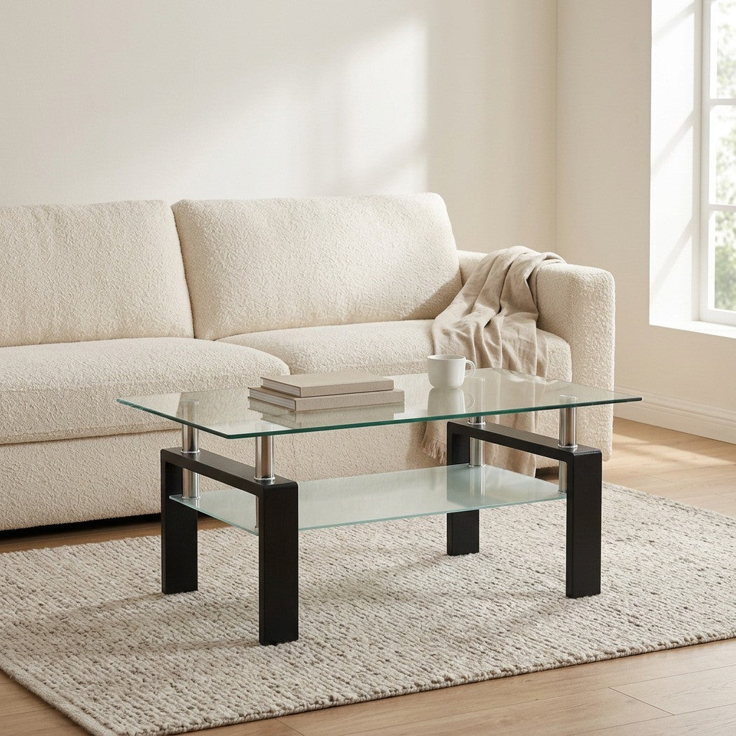 Black rectangular glass coffee table with shelf styled in front of a living room sofa