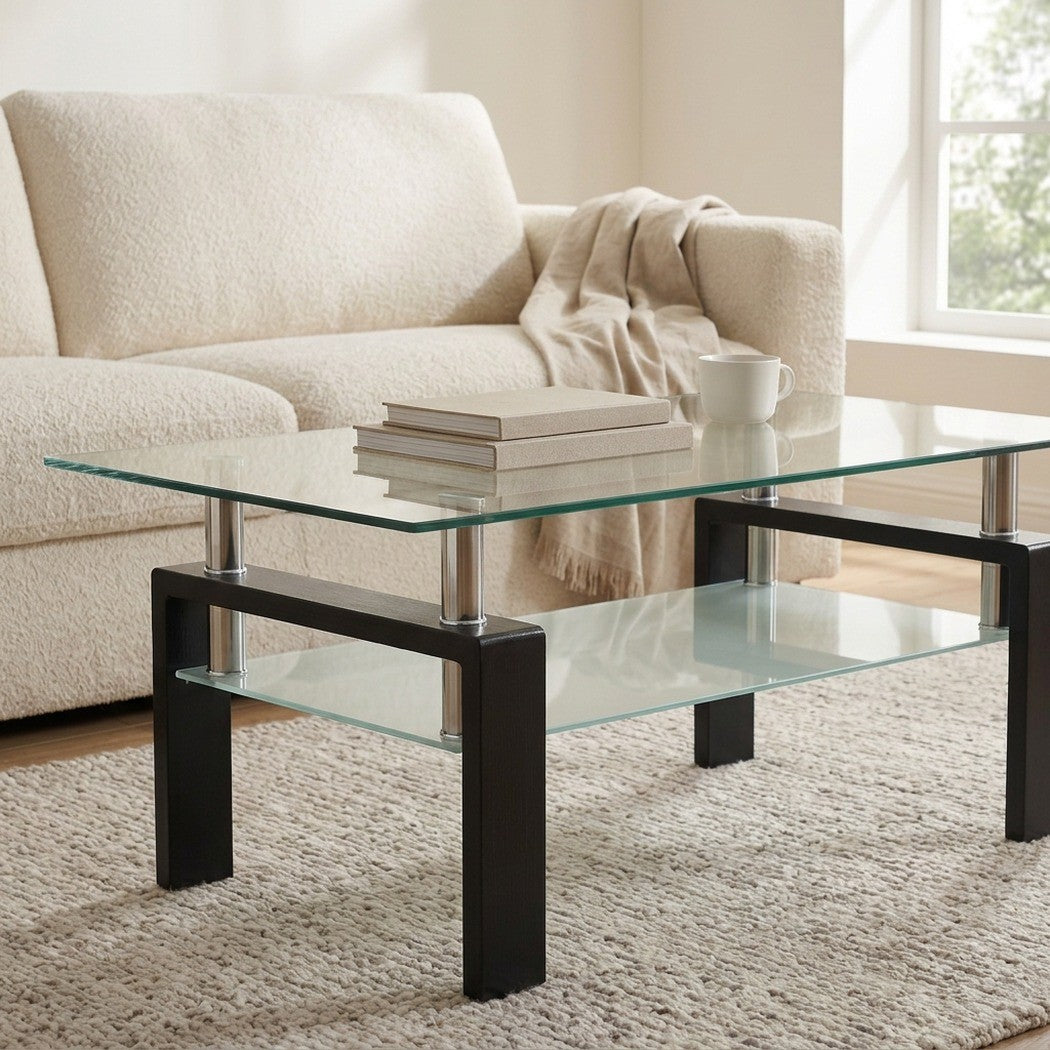 Two-tier black glass coffee table in a bright living room beside an armchair