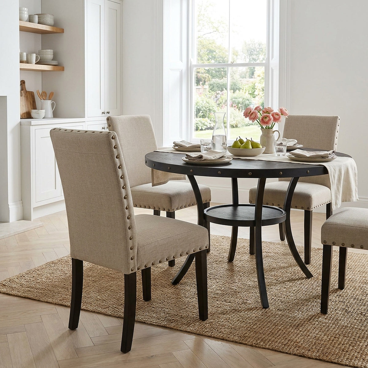 Seat-height view of a tan nailhead dining chair beside the round table, right-hand chair cut at the frame (close-up detail)