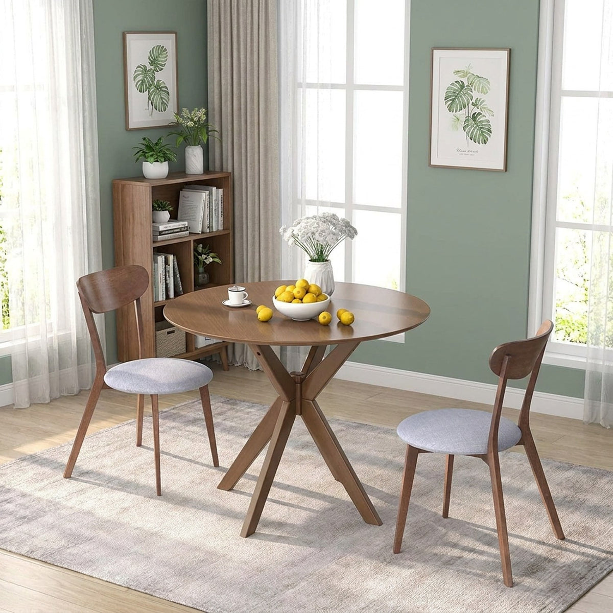 Round walnut table and two chairs in a sage green study corner with tea, lemons and flowers