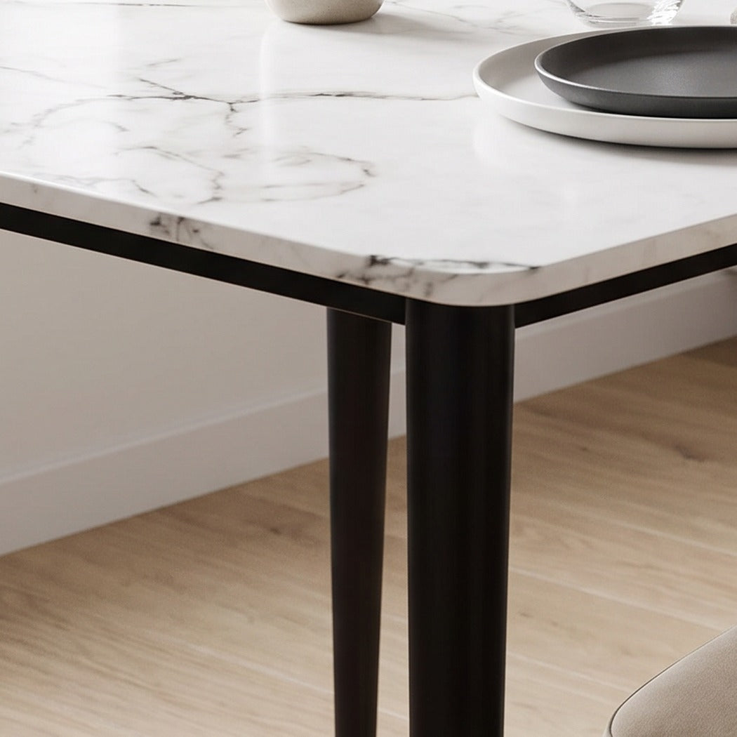 Tapered dark bronze table leg standing on an oak floor (close-up detail)
