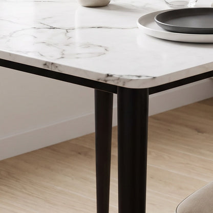 Tapered dark bronze table leg standing on an oak floor (close-up detail)