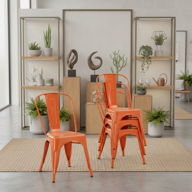 Stackable vibrant rust dining chairs in orange metal, shown in a modern, plant-filled showroom.