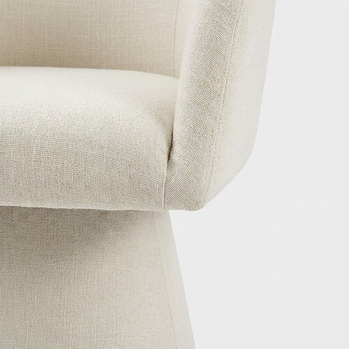 Cushion edge meeting a fabric-wrapped tapered pedestal base (close-up detail)