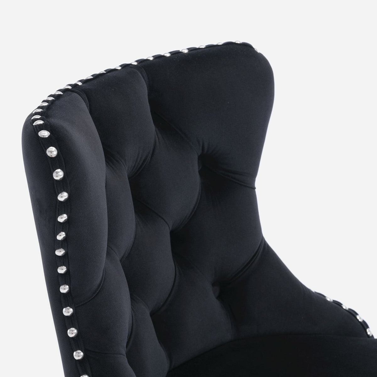 Diamond button tufting and silver nailhead row on the black velvet wingback, close up