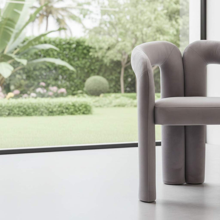 Velvet dining armchairs in soft gray with curved backs and plush upholstery by a large window.