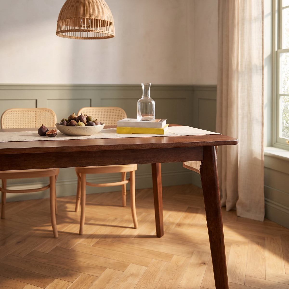Low view down the walnut-finish table in the breakfast room, window light across the herringbone floor