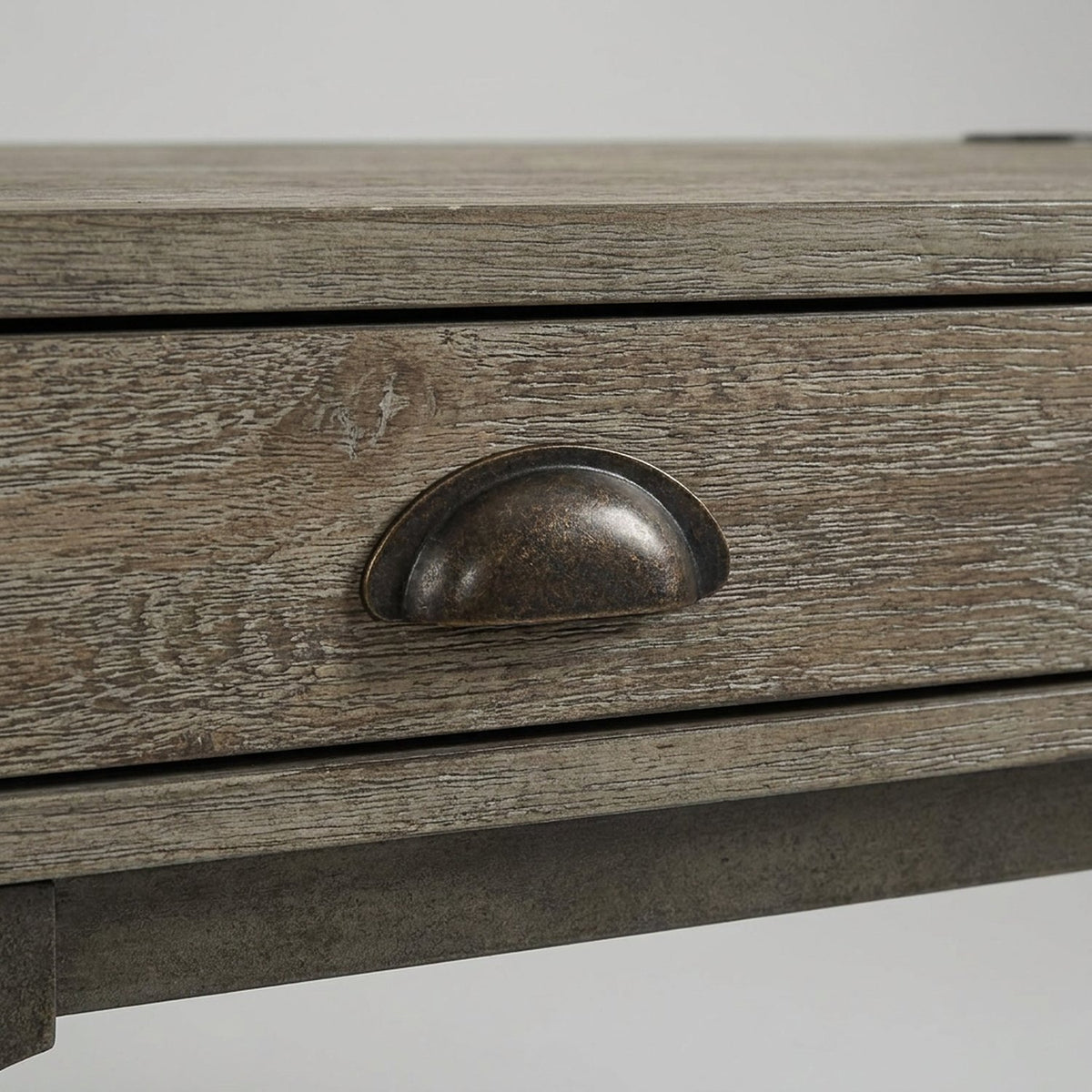 Aged bronze cup pull on a weathered oak drawer front (close-up detail)
