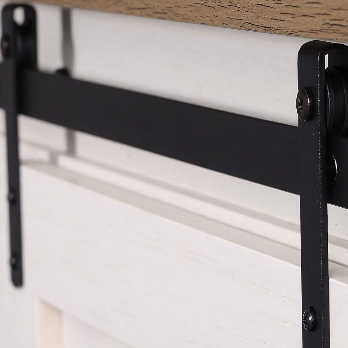 Matte black barn-door track with two hangers above the drawers, close up