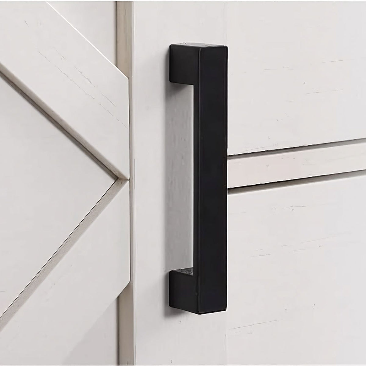 Square black bar handle beside an X-panel door, close up
