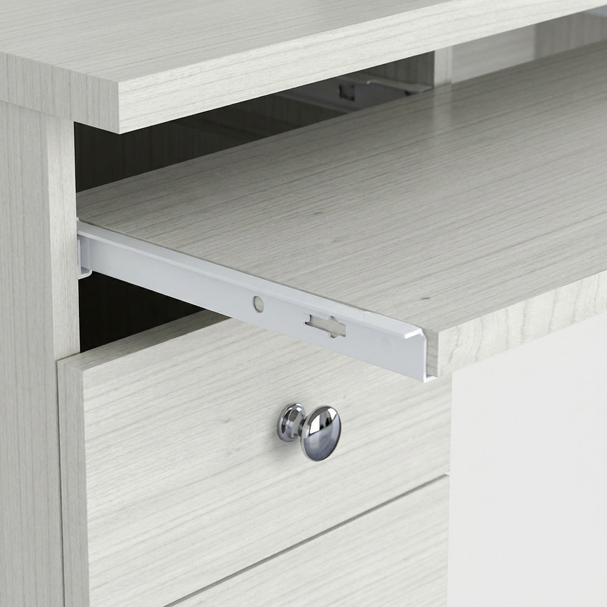 Close-up of the pull-out keyboard tray on its slide rail above a drawer with a chrome knob (close-up detail)