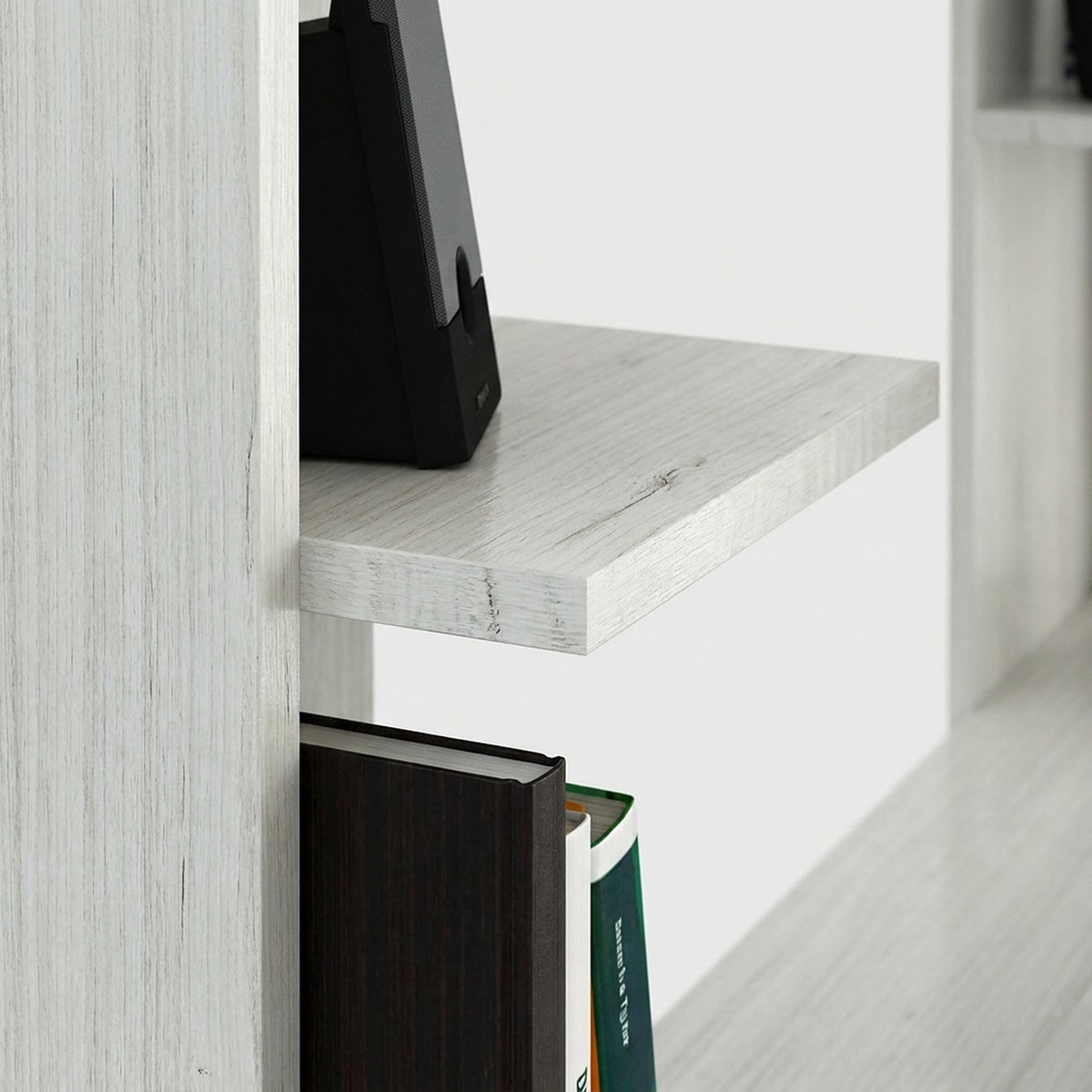 Close-up of a hutch shelf edge on a white wood computer desk with a speaker and books on the shelves