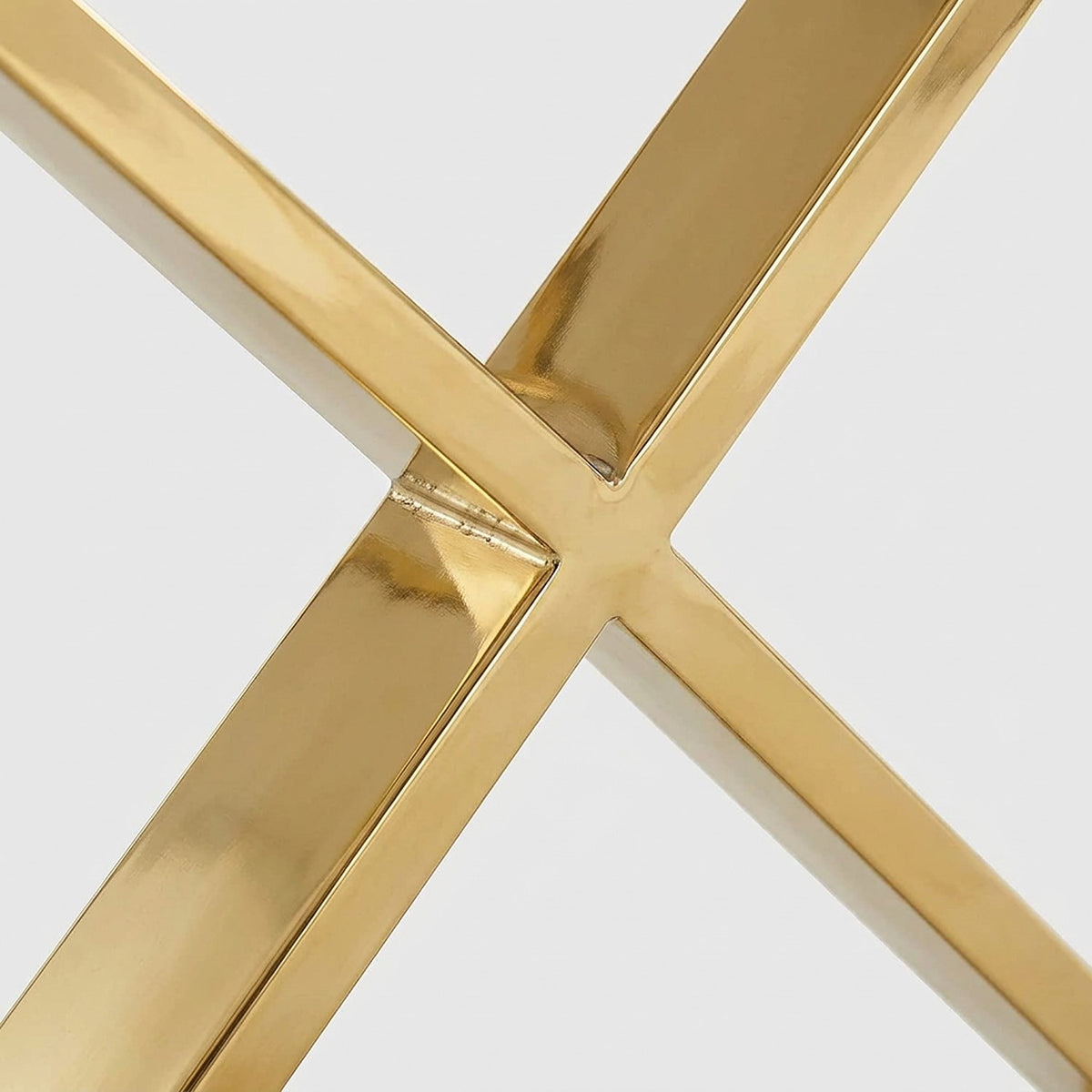 Close-up of the polished gold stainless steel X legs of the white dining table crossing