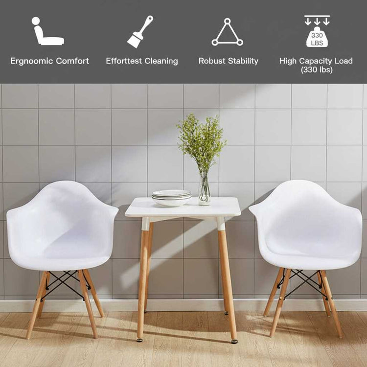 Set of 2 white mid-century molded dining arm chairs with wooden legs beside a small white table.