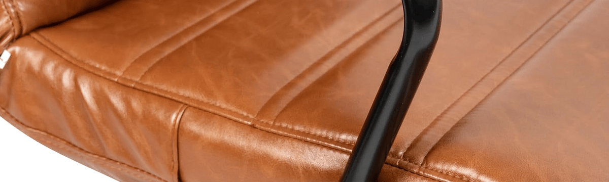 Close-up of the stitched leathersoft seat front edge beside the black arm post