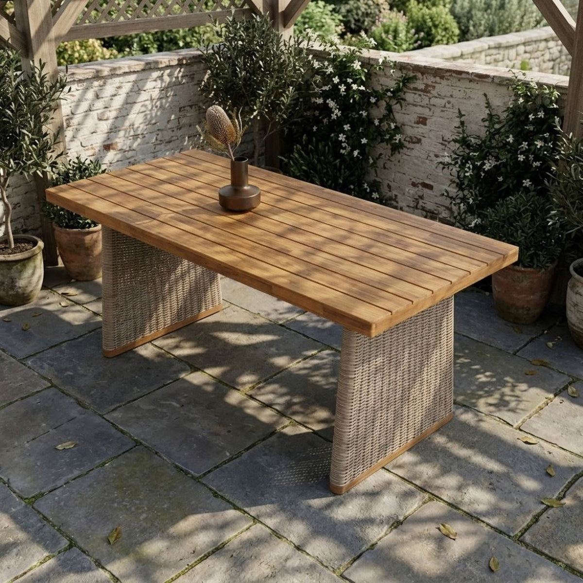 Acacia and wicker table under a pergola on a stone terrace, olive trees in pots around it