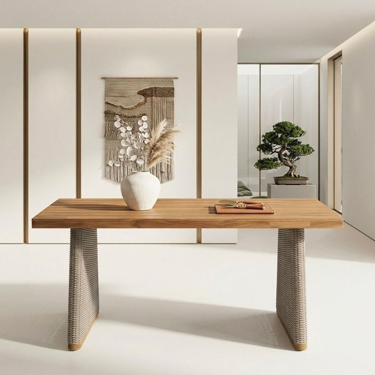 The table in a bright gallery room with a woven wall hanging and a white vase