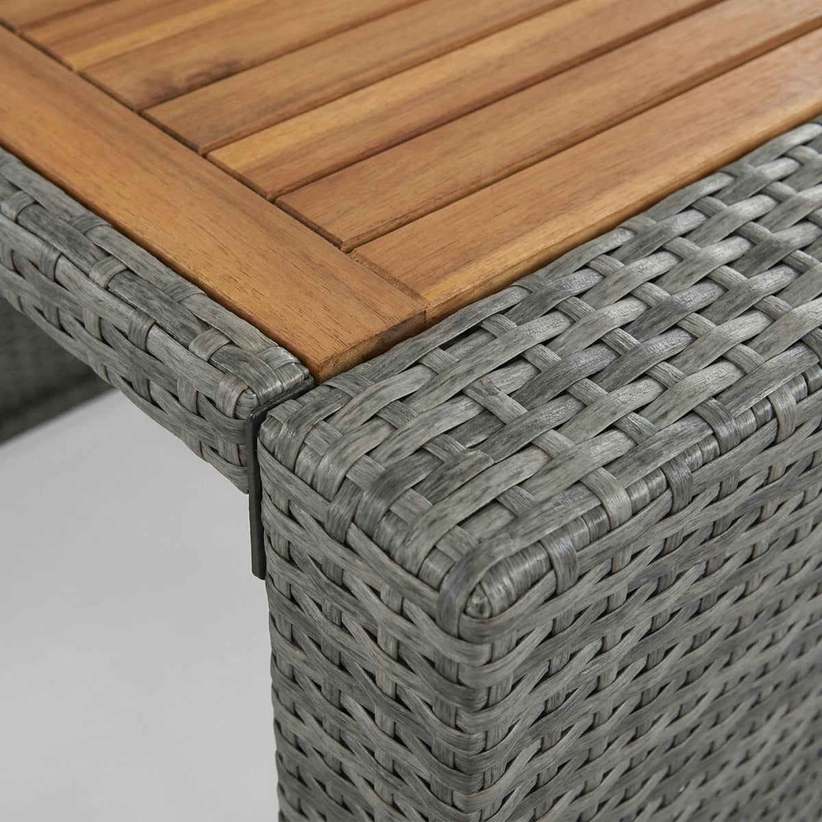 Slatted acacia tabletop meeting the gray wicker corner (close-up detail)