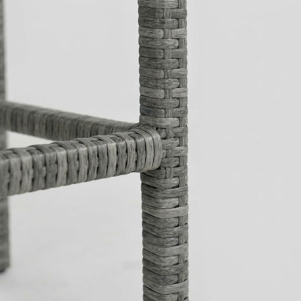Wicker-wrapped footrest rail on the bar stool leg (close-up detail)