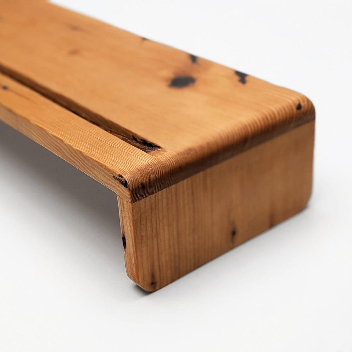 Rounded corner where the reclaimed top bends into the leg, natural finish, with knots and nail marks (close-up detail)