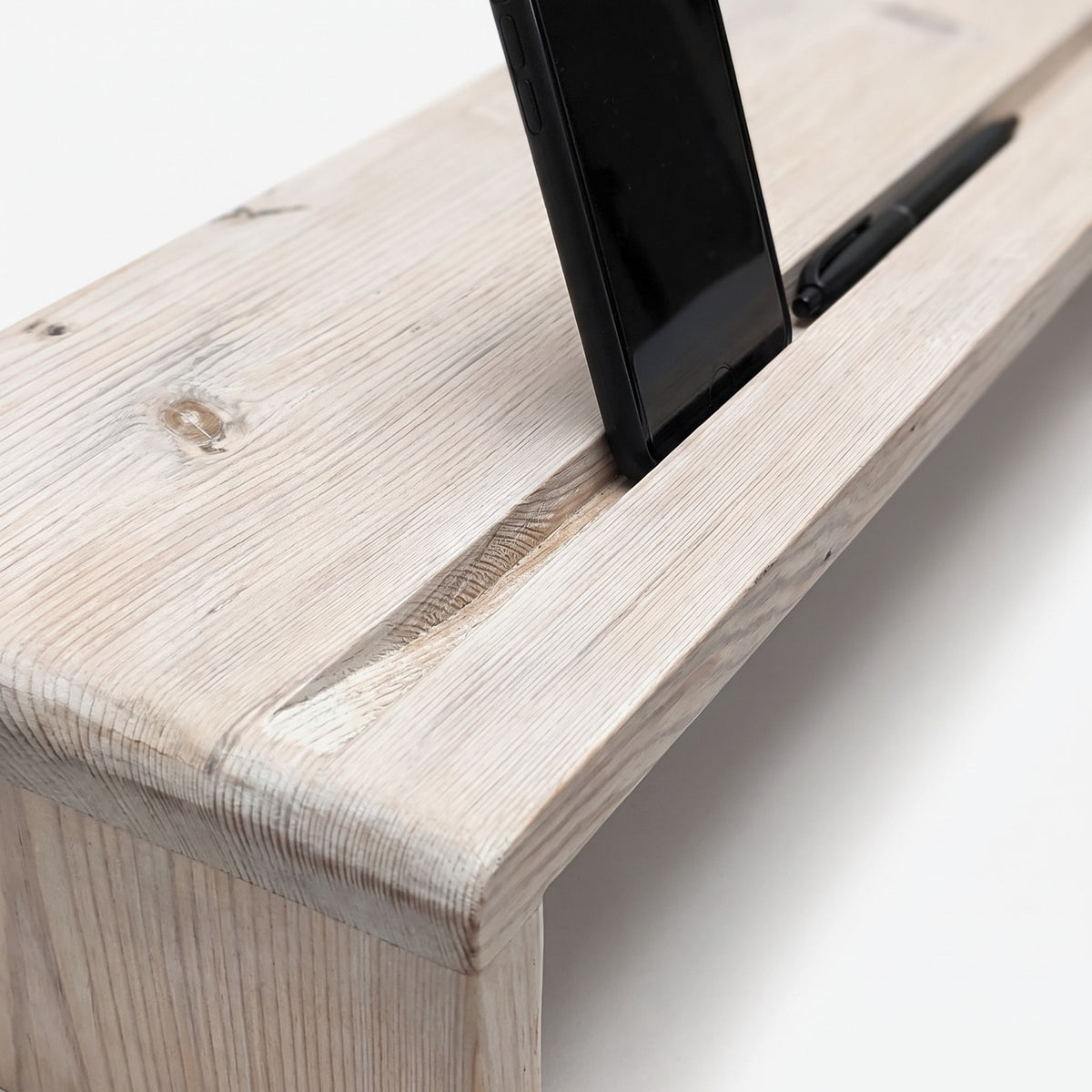Phone and pen standing in the front slot along whitewashed reclaimed grain (close-up detail)