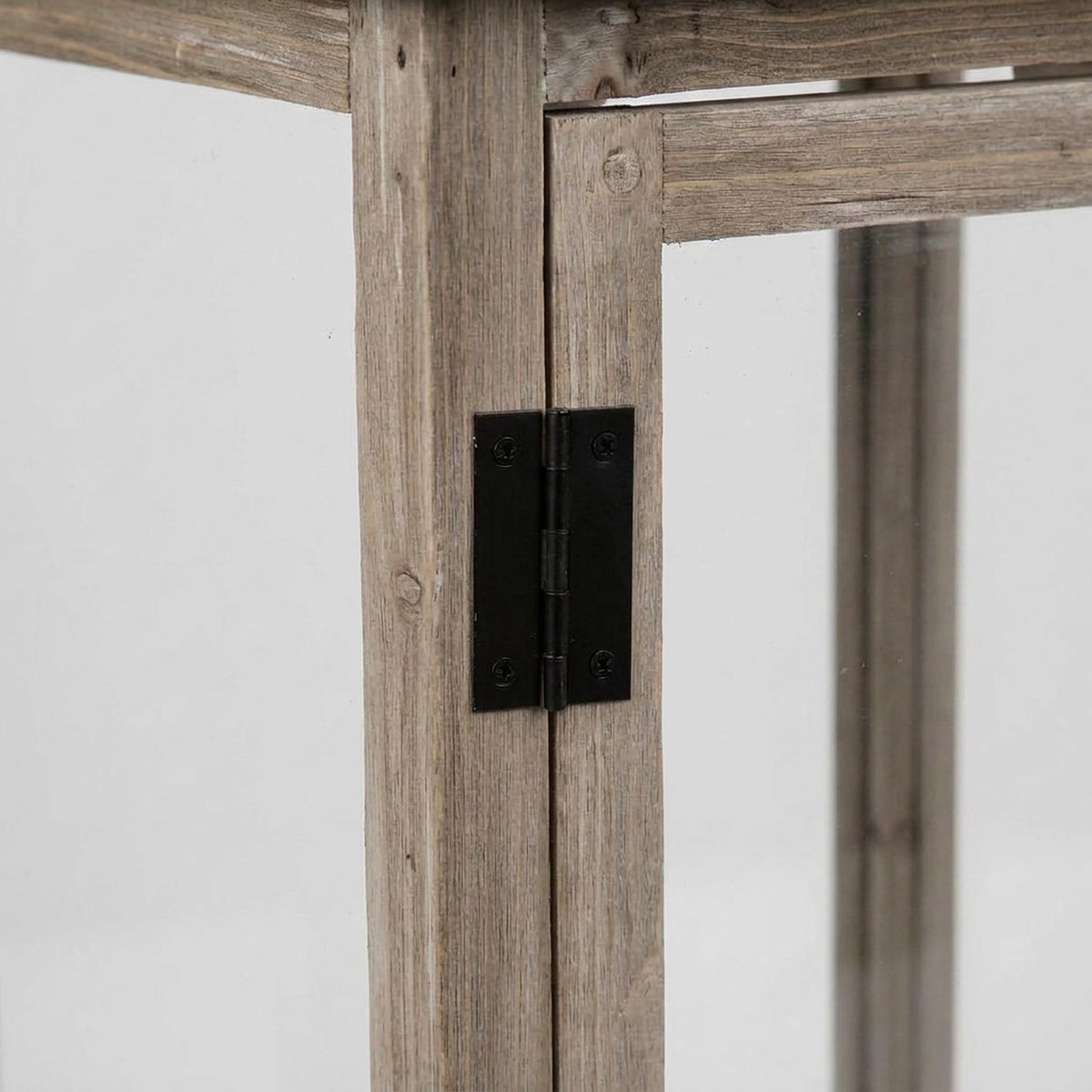 Black leaf hinge joining the fir corner post to the glass door of a wooden lantern (close-up detail)