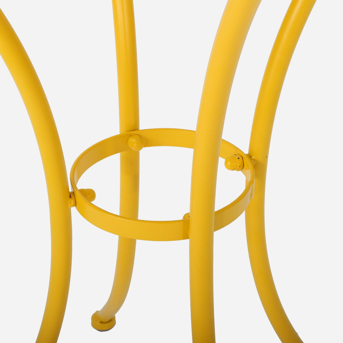 Ring brace joining the curved yellow metal table legs (close-up detail)