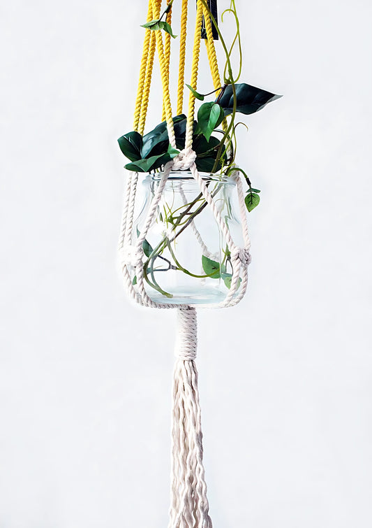 Handmade cotton hanging planter with a yellow rope holding a glass vase on a white background